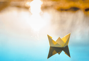 yellow floating paper boat. colorful sailing ship in big blue spring puddle, river water on winter s