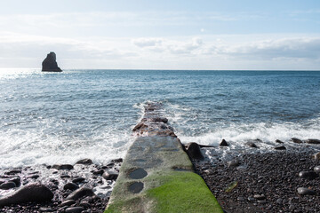 Wall Mural - Beautiful ocean view with black stone beach, waves and stone path into the water. Madeira volcanic island