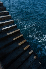 Wall Mural - Concrete steps lead to the ocean on a sunny day. Minimalism photo with light and shadows