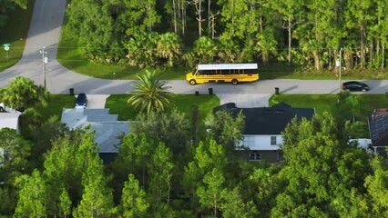 Canvas Print - Aerial view of american yellow school bus driving on suburban street for picking up children for their lessongs in early morning. Public transportation in the USA