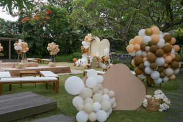 Creative gender neutral baby shower or birthday decoration in the garden. Bohemian style outdoor event set up with balloons. White cream peach caramel balloon arch kit.