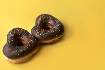 two donuts in a heartshape on a yellow background. Concept for Valentine's Day. Valentine's Day bakery. space for text, copy space, flatly