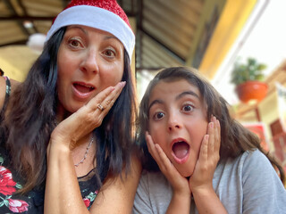 Sticker - Family Tropical Christmas. Young girl together with her mom wearing Christmas Hat