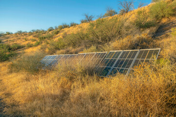 Poster - Solar panels in a grassy mountain landscape with clear blue sky background. A renewable source of energy using sunlight to generate green electricity.