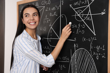 Wall Mural - Happy teacher explaining mathematics at chalkboard in classroom