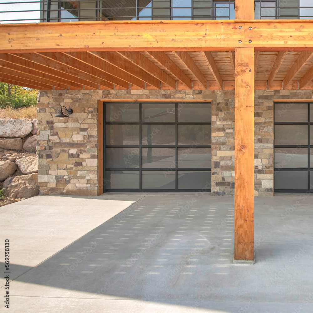 Square Two glass garage door of a modern custom house with stone veneer ...