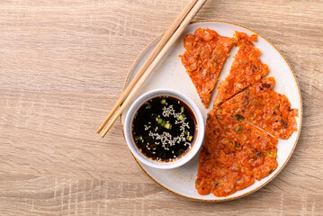 Canvas Print - Kimchi pancake (Kimchi jeon or kimchi buchimgae) on plate eating with soy dipping sauce, Korean food, Table top view