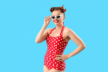 Poster - Young pin-up woman in polka dot swimsuit on blue background