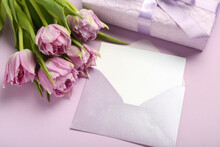 Envelope With Blank Card, Gift And Tulips On Lilac Background, Closeup. Hello Spring