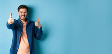 Positive Smiling Guy Showing Thumbs Up And Smiling, Complimenting You, Praising Good Job, Well Done Gesture, Standing On Blue Background