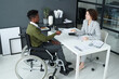 © AnnaStills - High angle view of businesswoman having job interview with man with disability while they sitting at table in modern office