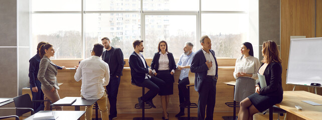 Wall Mural - Diverse groups of colleagues communicating with each other during break on business presentation in office meeting room. Business people discuss presentation, work, share thoughts and ideas. Panorama.