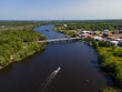 Wide river with passenger boat travelling under the bridges in Milton, Florida. River waterway in between the land areas with trees on left and buildings on the right connected by the bridges.