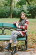 © Cavan Images - young woman in a warm coat sits on a bench in an autumn park