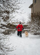 © Cavan Images - Boy and fluffy dog playing in the snow together on a winter day.