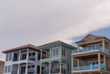 Fototapeta Miasto - Low angle view of beach houses with balconies against the white giant clouds at Destin, Florida. Three modern beach houses architecture with balconies.