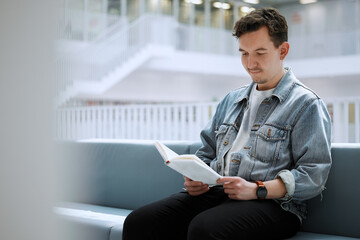 Wall Mural - Reading, books and relax man in library for university, college or research focus with philosophy scholarship. Student person of English language, education or knowledge on history studying on campus