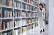 © K Davis/peopleimages.com - Woman in library, student search for book and research project, reading with education and learning at university campus. Knowledge, story and fiction with textbook, study and browsing bookshelf