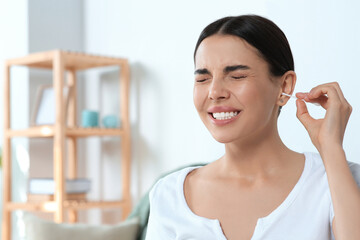 Poster - Young woman cleaning ear with cotton swab at home