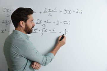 Wall Mural - Mature teacher explaining mathematics at whiteboard in classroom