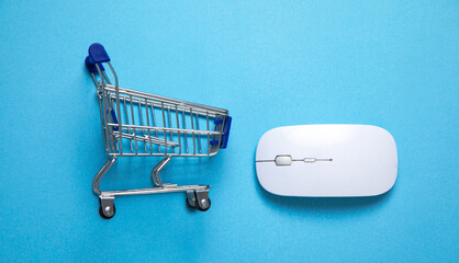 Wall Mural - Shopping cart and computer mouse on the blue background.