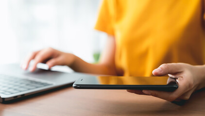 Wall Mural - Hand holding smartphone and using laptop.