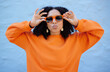 © K Davis/peopleimages.com - Fashion, sunglasses and black woman with kiss face, summer style and beauty with hairstyle on blue background. African American model hands with designer brand frame and trendy, stylish and pose