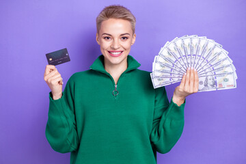 Photo of positive pretty lady wear green sweater holding cash fan bank credit card isolated violet color background