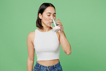 Young woman wear white clothes hold transparent glass drink clear fresh pure still water close eyes isolated on plain pastel light green background. Proper nutrition healthy fast food choice concept.