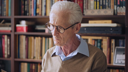 Senior male journalist reading historical articles in the library, doing research