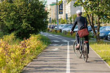 stylish businessman in helmet cycling on bike path in sunny day.