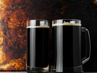 Wall Mural - Two mugs of dark draft beer, rusty background