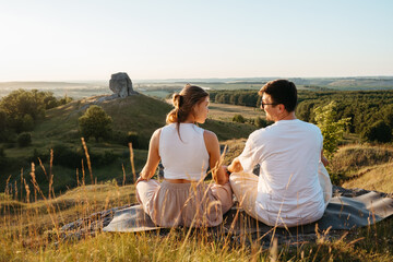 man and woman practicing yoga and meditation outdoors at sunset with scenic landscape and nature mir