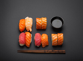 Poster - Set of traditional Japanese sushi and rolls top view with soy sauce and chopsticks on dark black minimal background. Sushi with salmon, tuna and shrimp