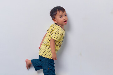 Cheerful toddler Asian kid boy 2 years old wearing a yellow t-shirt looking at camera with open mouth isolated on white background