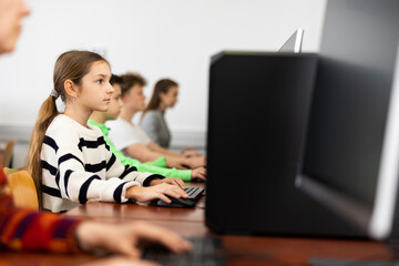 Modern teen schoolgirl learning basics of programming in group course in computer college..