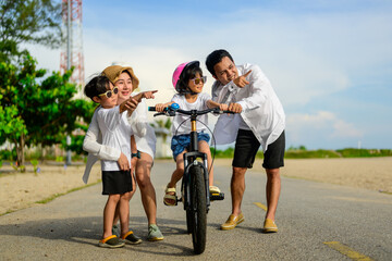 Wall Mural - Family on beach vacation, Father and mother wearing safety helmet to cheerful son before riding bicycle, Family with beach travel