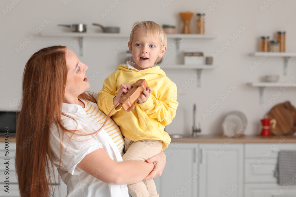 Mother and her little son with toy car in kitchen