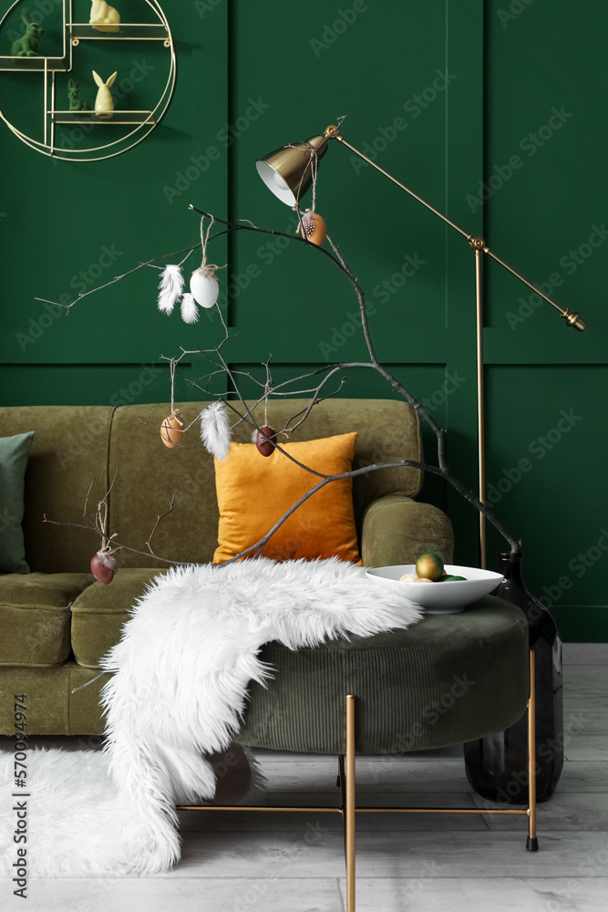 Vase with branches and painted Easter eggs on table in living room