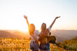 © Marcio - Two female friends together with arms raised having fun and enjoying the moment with sunset in the background. Concept of friendship and togetherness.
