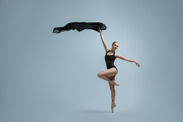 Wall Mural - Graceful young ballerina practicing dance moves with black veil on grey background. Space for text