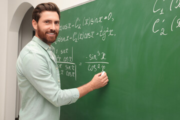 Wall Mural - Happy teacher explaining mathematics at chalkboard in classroom