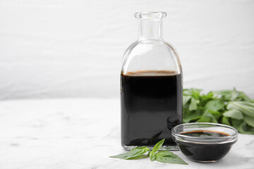 Wall Mural - Organic balsamic vinegar and basil on white marble table, space for text