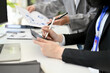 © bongkarn - Side view of a group of businesspeople working together in the office, brainstorming.