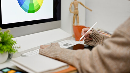 Poster - side view of a female graphic designer working at her desk, using computer and graphic tablet