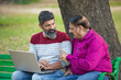 © PRASANNAPIX - Two indian people using laptop at park.
