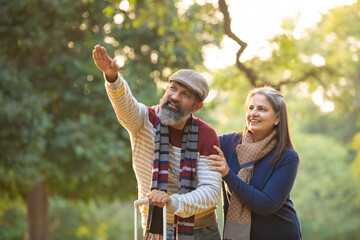 Indian Senior couple with travel bag at park.