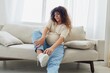 © SHOTPRIME STUDIO - Pregnant woman sitting on the couch at home and wearing comfortable shoes for pregnancy with a problem due to the stomach, headache, pregnancy and motherhood difficulties, severe fatigue