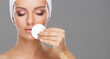 © Acronym - Young woman cleaning her face with a cotton pads. Girl removing cosmetics with hygienic discs.