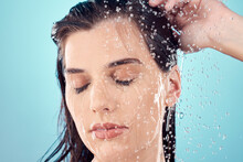 Water Splash, Hair Care And Face Of Woman In Shower In Studio Isolated On A Blue Background. Beauty, Eyes Closed And Young Female Model Washing, Cleaning Or Bathing For Hygiene, Skincare And Health.